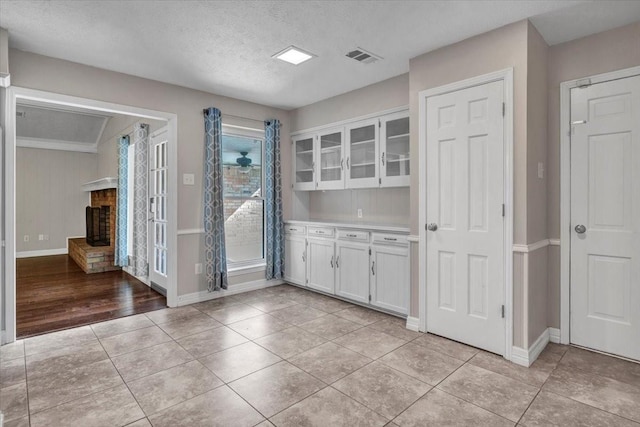 kitchen featuring a textured ceiling, white cabinets, a fireplace, and light tile patterned floors