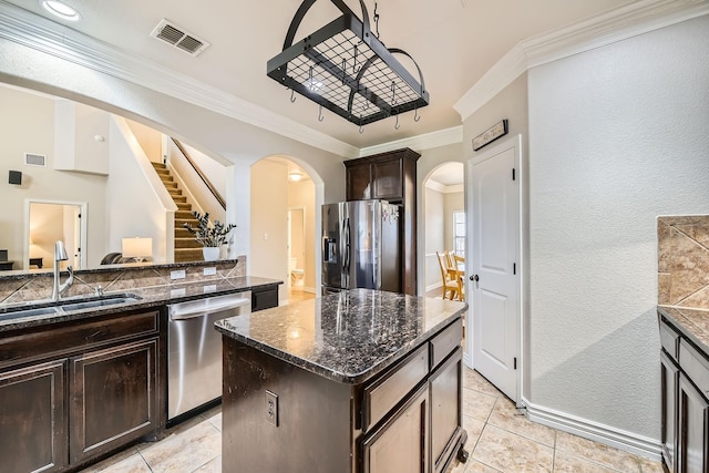 kitchen featuring stainless steel appliances, a center island, sink, and dark stone counters