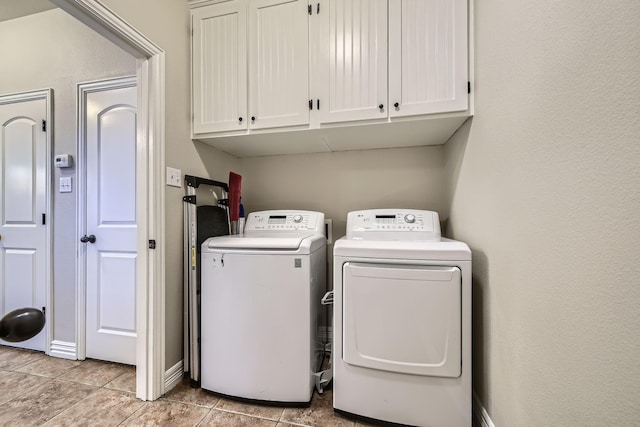 clothes washing area featuring light tile patterned flooring, cabinets, and washing machine and dryer