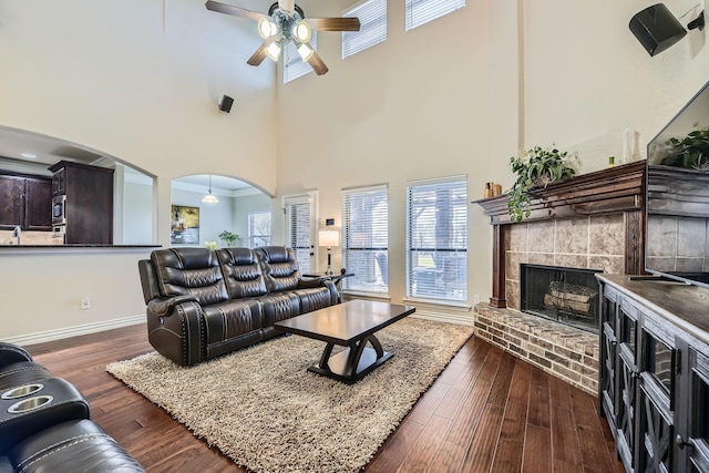 living room featuring ceiling fan, a brick fireplace, and dark hardwood / wood-style flooring