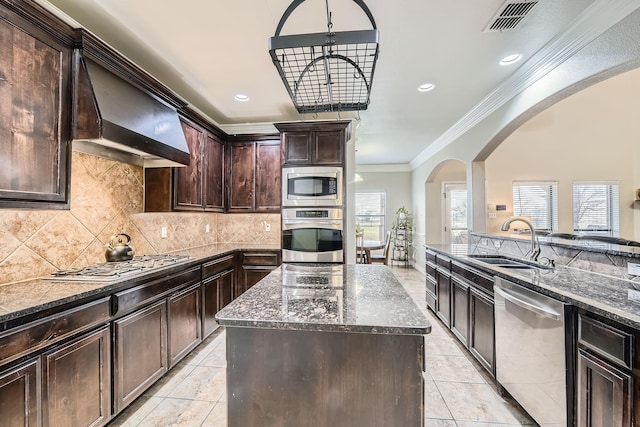 kitchen with a kitchen island, sink, dark stone countertops, dark brown cabinetry, and stainless steel appliances