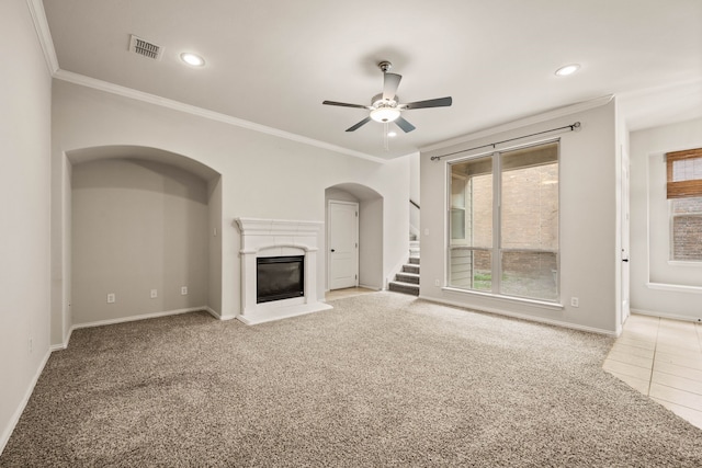 unfurnished living room featuring carpet, a glass covered fireplace, visible vents, and crown molding