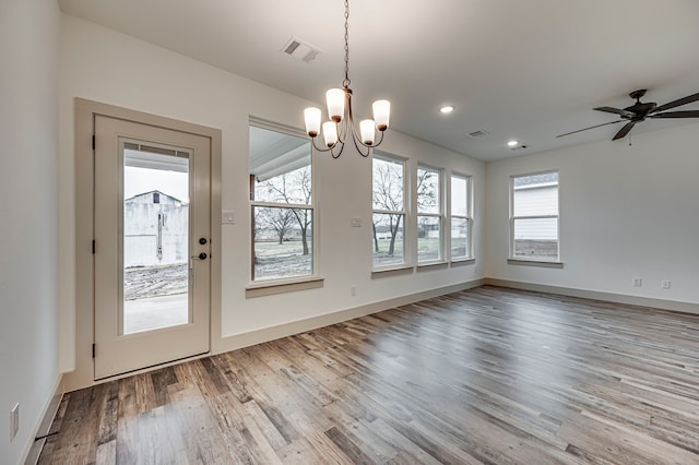 unfurnished dining area featuring wood-type flooring and ceiling fan with notable chandelier