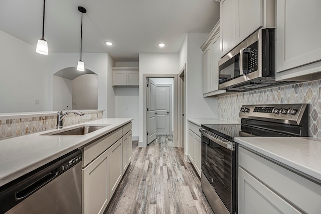 kitchen featuring a sink, decorative backsplash, appliances with stainless steel finishes, and light countertops