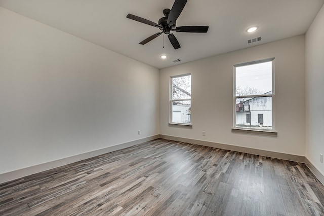 spare room featuring ceiling fan, visible vents, baseboards, and wood finished floors