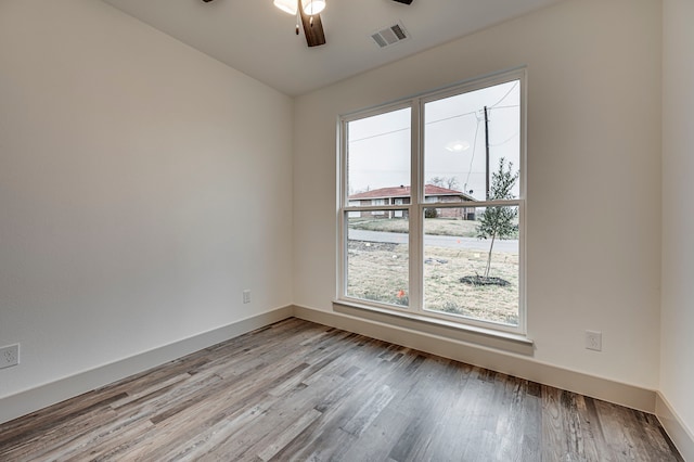 empty room featuring ceiling fan, plenty of natural light, and light wood-type flooring