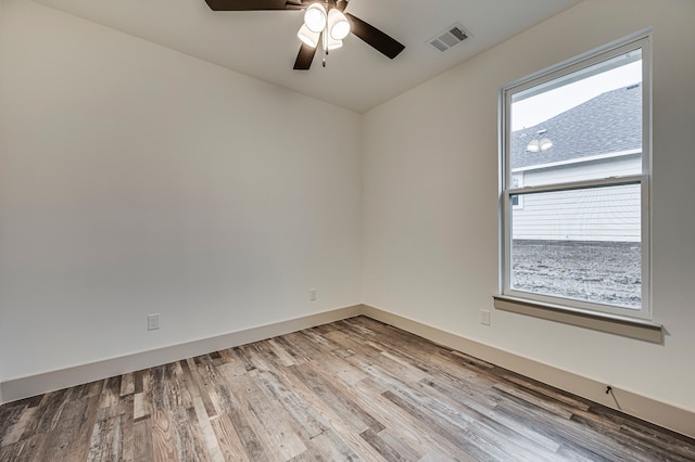 spare room with ceiling fan, visible vents, baseboards, and wood finished floors