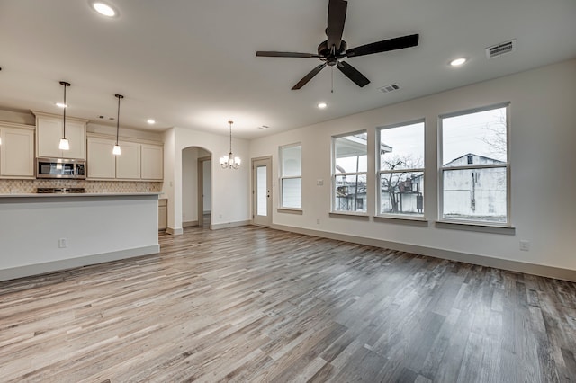 unfurnished living room featuring recessed lighting, visible vents, arched walkways, and a ceiling fan