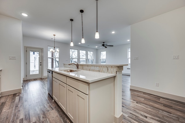 kitchen featuring a sink, dishwasher, an island with sink, light countertops, and dark wood-style flooring