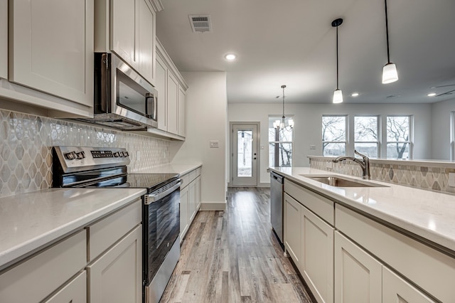 kitchen featuring visible vents, light wood finished floors, a sink, stainless steel appliances, and light countertops