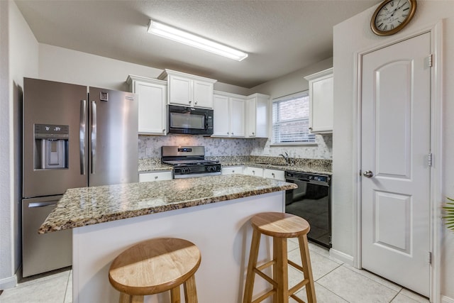 kitchen with a kitchen island, a breakfast bar area, light stone counters, and black appliances