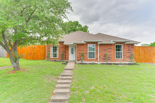 ranch-style house with a front yard, a shingled roof, brick siding, and fence