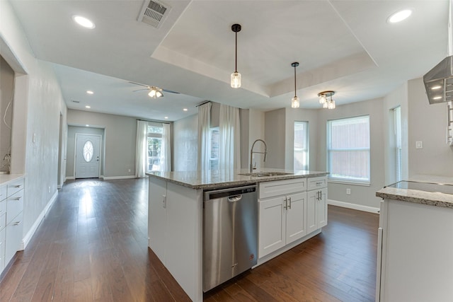 kitchen with sink, white cabinets, a kitchen island with sink, stainless steel dishwasher, and a tray ceiling