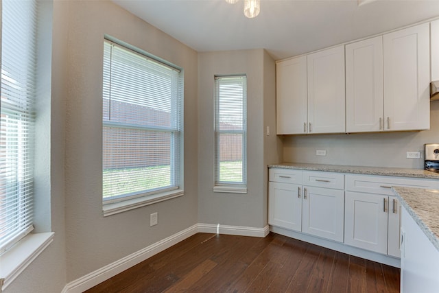 kitchen featuring light stone counters, dark wood-type flooring, white cabinets, and baseboards