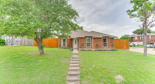 ranch-style house with fence, roof with shingles, a front yard, and brick siding