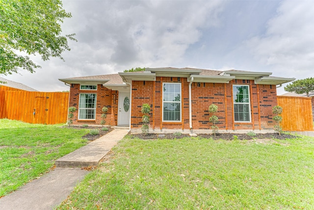 view of front of house featuring brick siding, fence, a front yard, and a gate