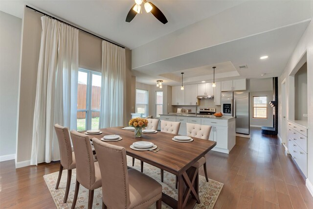 dining space featuring a raised ceiling, visible vents, baseboards, dark wood-style flooring, and a ceiling fan