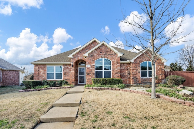 single story home with roof with shingles, fence, a front lawn, and brick siding