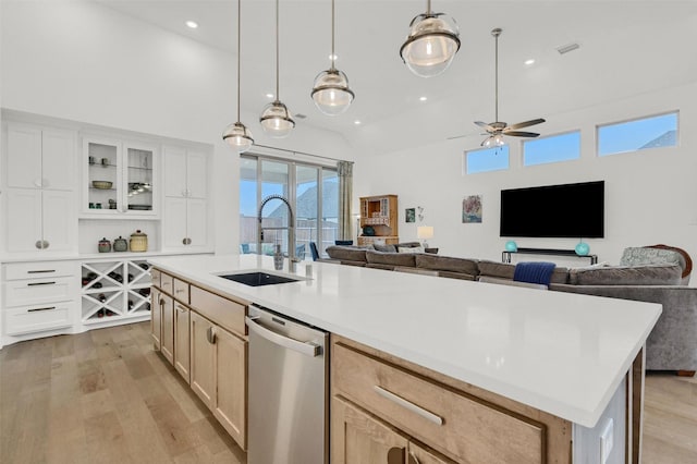 kitchen featuring light brown cabinetry, sink, decorative light fixtures, dishwasher, and a kitchen island with sink