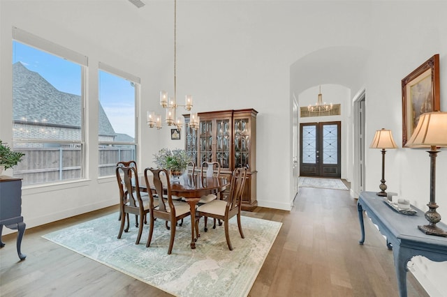 dining space with french doors, wood-type flooring, and a chandelier