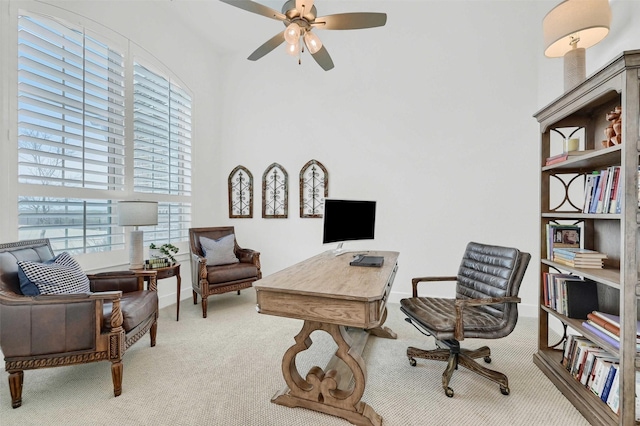 carpeted home office with a high ceiling and ceiling fan