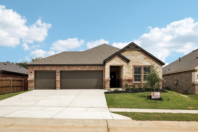 view of front of home with roof with shingles, a front yard, fence, concrete driveway, and an attached garage