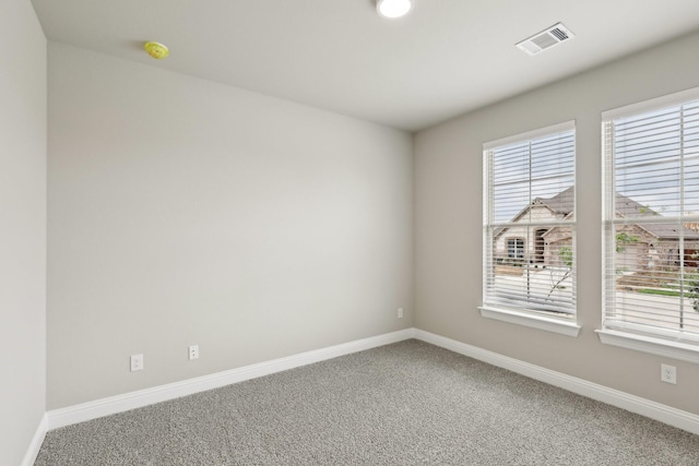 spare room with baseboards, visible vents, and carpet