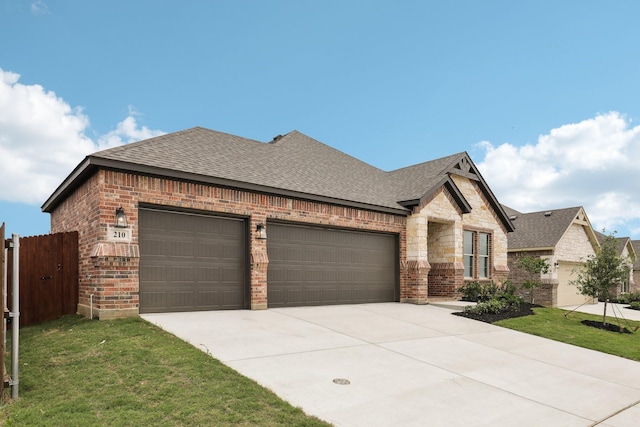view of front of house featuring driveway, a front yard, roof with shingles, brick siding, and an attached garage