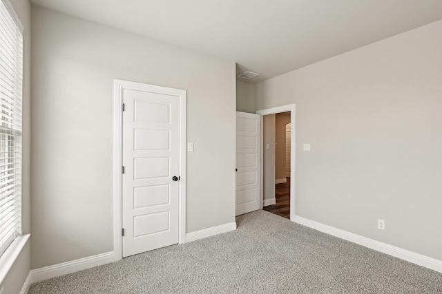 unfurnished bedroom featuring visible vents, carpet, baseboards, and multiple windows