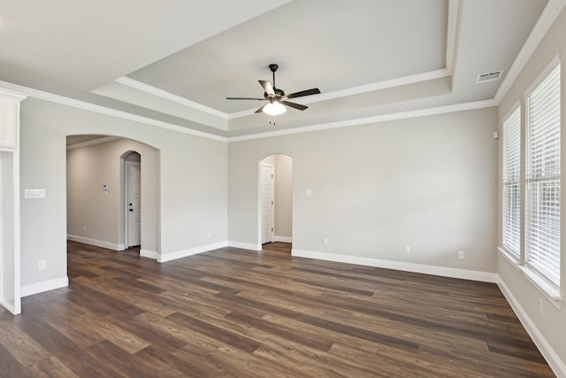 spare room with a ceiling fan, visible vents, arched walkways, a tray ceiling, and dark wood-type flooring