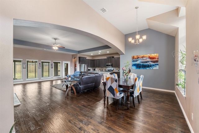 dining space featuring lofted ceiling, ceiling fan with notable chandelier, and dark wood-type flooring