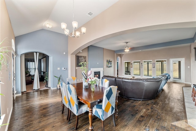 dining area featuring dark wood-type flooring, ceiling fan with notable chandelier, and vaulted ceiling