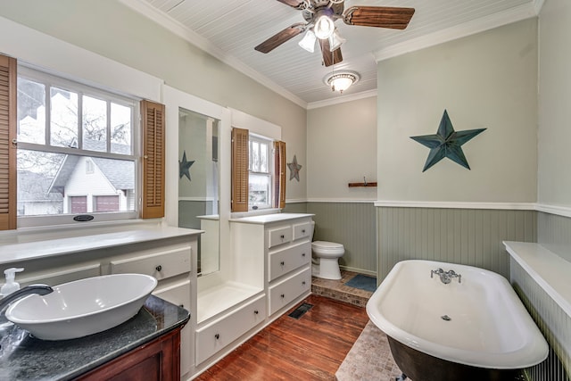 bathroom with a tub to relax in, toilet, crown molding, vanity, and hardwood / wood-style floors