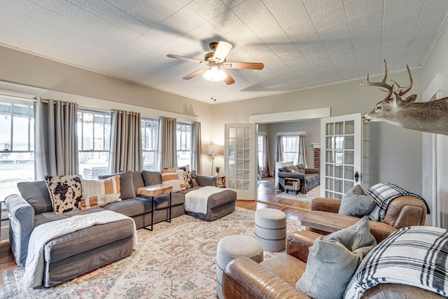 living room featuring plenty of natural light, light wood-type flooring, ceiling fan, and french doors