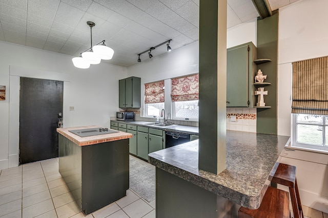 kitchen with a breakfast bar, black appliances, sink, green cabinets, and kitchen peninsula