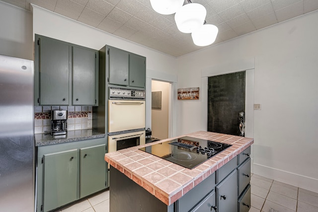 kitchen featuring tasteful backsplash, a center island, stainless steel refrigerator, double wall oven, and black electric stovetop