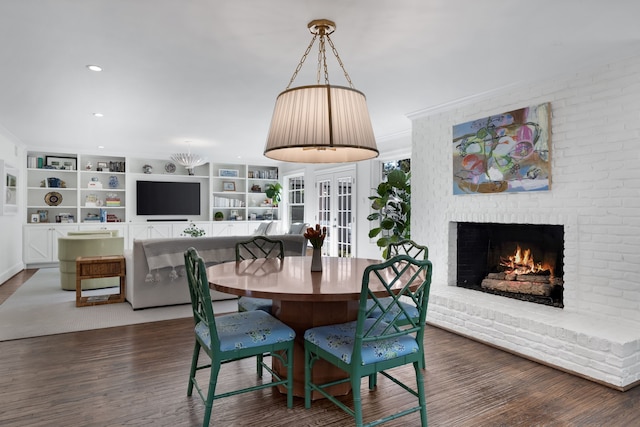 dining area with crown molding, dark hardwood / wood-style floors, and a brick fireplace