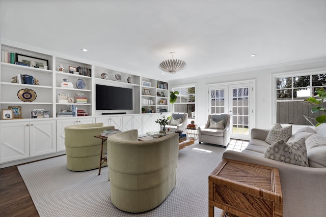 living room with wood-type flooring, built in features, crown molding, and french doors