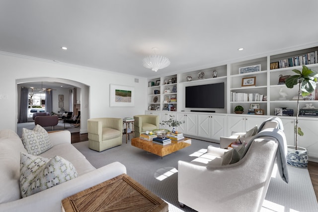 living room with ornamental molding, light wood-type flooring, a chandelier, and built in shelves