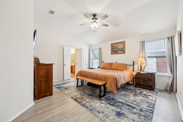 bedroom featuring vaulted ceiling, ensuite bathroom, ceiling fan, and light hardwood / wood-style flooring