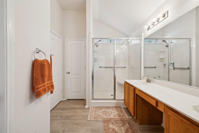 bathroom featuring a shower with door, vaulted ceiling, hardwood / wood-style floors, and vanity