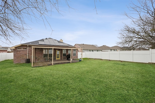 back of house featuring a patio, a lawn, central AC unit, and solar panels