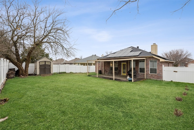 rear view of property featuring a storage shed, a yard, a patio, and solar panels