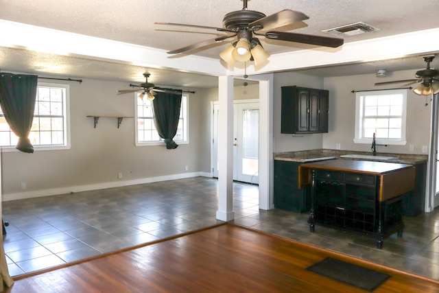 kitchen featuring sink, a wealth of natural light, a textured ceiling, and dark tile patterned flooring