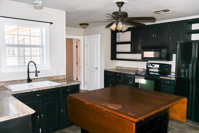 kitchen with sink, dark tile patterned flooring, ceiling fan, black appliances, and a textured ceiling