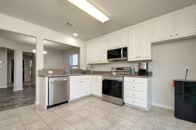 kitchen featuring white cabinetry, appliances with stainless steel finishes, sink, and light tile patterned floors