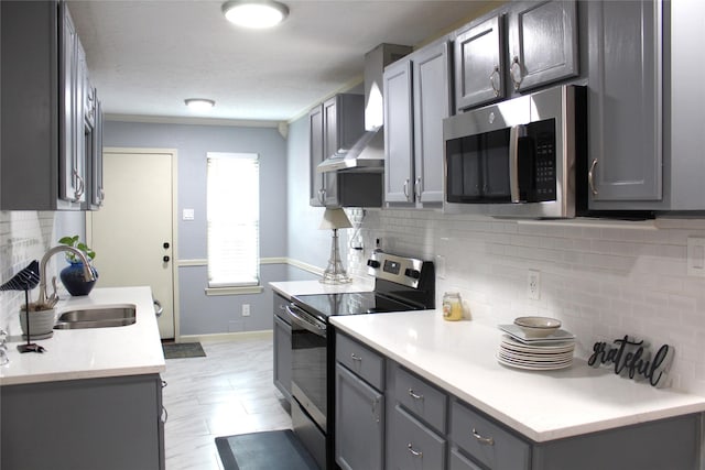 kitchen with sink, gray cabinets, wall chimney exhaust hood, and appliances with stainless steel finishes