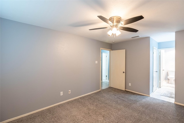 unfurnished bedroom with ceiling fan, light colored carpet, and ensuite bath