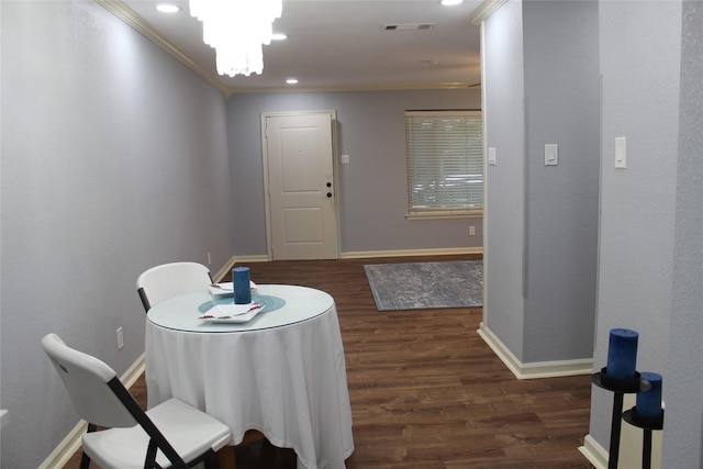 dining space with dark hardwood / wood-style flooring, ornamental molding, and an inviting chandelier