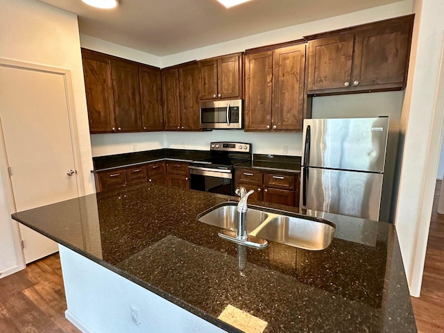 kitchen featuring stainless steel appliances, sink, and dark stone countertops